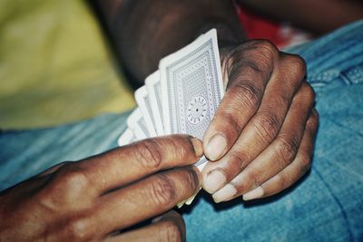 Cropped hands holding playing cards at home