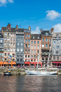 Buildings by canal against sky in city