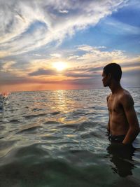 Shirtless man looking away in seashore