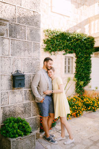 Happy couple standing against plants