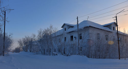 Snow covered houses and trees against sky