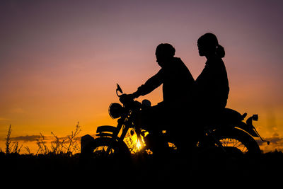 Silhouette man and woman riding motorcycle against sky during sunset
