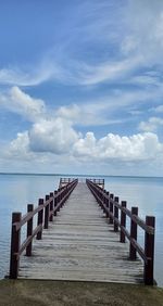 Empty pier over sea against sky