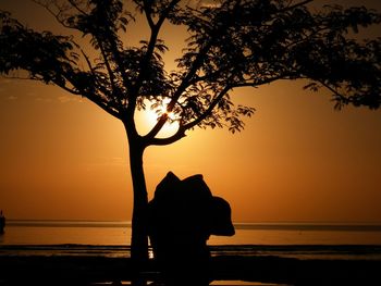 Silhouette tree by sea against sky during sunset