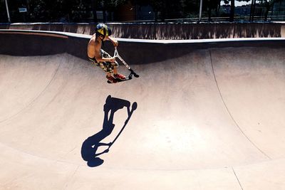 High angle view of boy with push scooter performing stunt at skateboard park