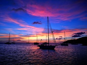 Sailboats sailing in sea at sunset