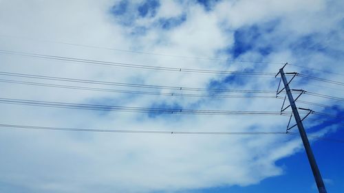 Low angle view of power lines against blue sky