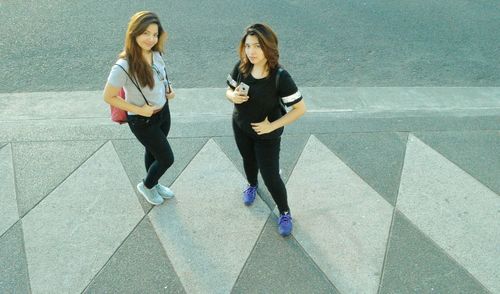 High angle portrait of friends standing on sidewalk by street