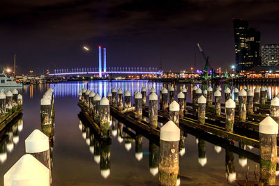 Illuminated pier over river against sky at night