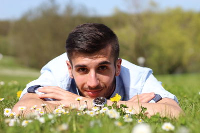 Portrait of young man lying on field