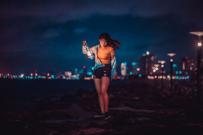 Full length of woman standing at beach against sky at night