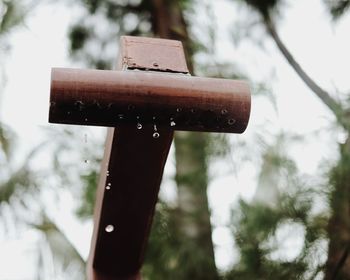 Close-up of cross against trees