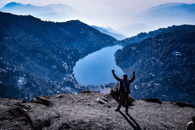 Rear view of man with arms raised against sky