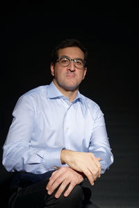 Portrait of young man standing against black background