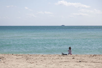 Rear view of man looking at sea against sky