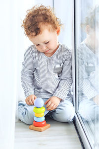 Cute little girl playing with colored pyramid while sitting at home