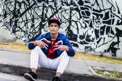 Full length portrait of young man sitting outdoors