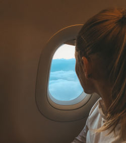 Woman looking through window while sitting in airplane