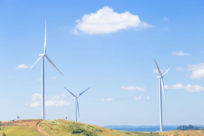 Windmills on field against sky