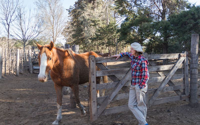 Woman standing with horse in farm