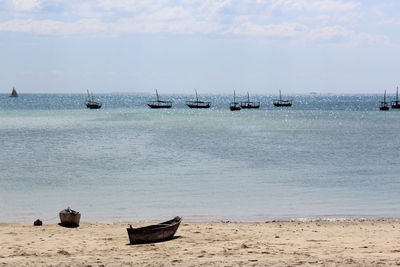 Sailboats moored on sea against sky