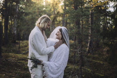 Smiling newly married couple looking at each other in forest during wedding