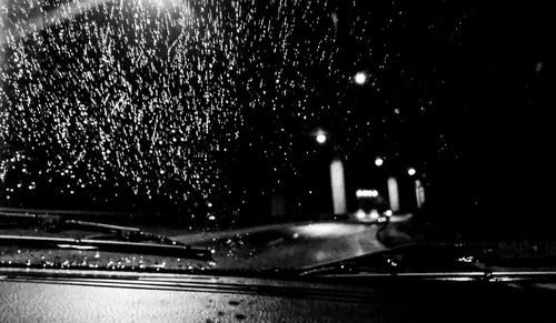 Illuminated city seen through wet windshield at night