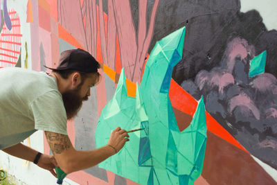 Young man painting on surrounding wall