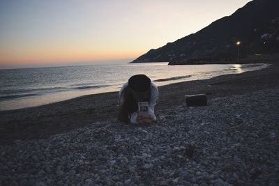 Woman on beach against sky during sunset