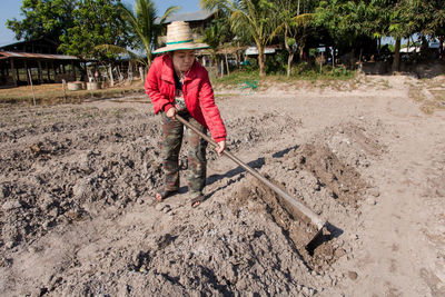 Full length of female farmer wearing hat while working in farm