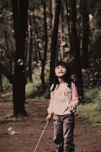 Girl looking at bubble in forest