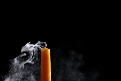 Close-up of yellow emitting smoke against black background