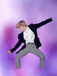 Low angle view of woman dancing against pink background