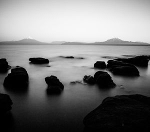 Rocks in sea against clear sky