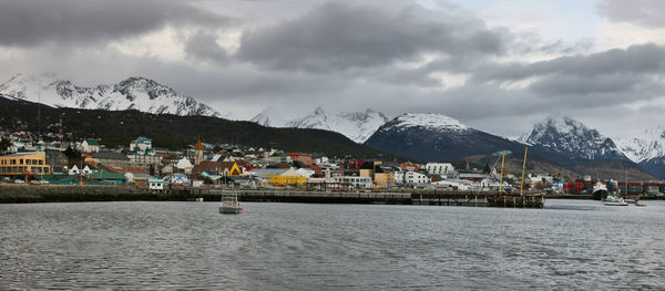 Scenic view of river by buildings against sky during winter