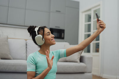 Midsection of woman using mobile phone while sitting on sofa at home