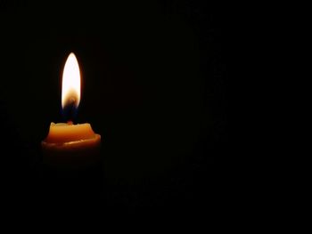 Close-up of lit candle in darkroom