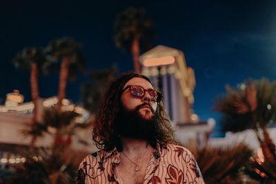 Low angle view of young man wearing sunglasses against sky at night