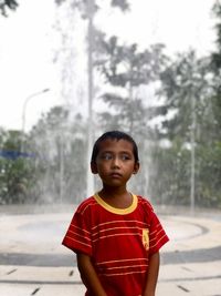 Portrait of young man standing against trees