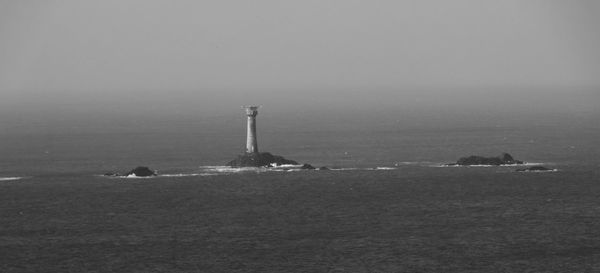 Lighthouse by sea against clear sky