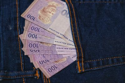 Directly above shot of paper currencies in jeans pocket