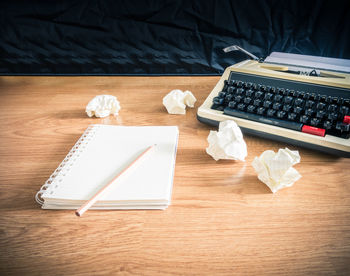 Close-up of book and pencil by typewriter on table