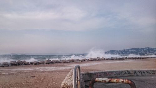 Scenic view of shore and sea against cloudy sky