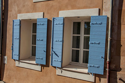 Detail of windows with blue shutters at sunset at the village of roussillon, in the french provence.