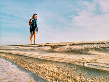 Full length of young woman on sand dune in desert