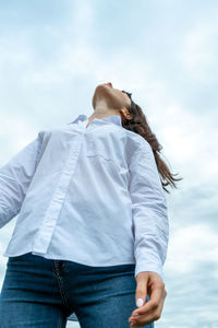 Low angle view of smiling woman standing against sky