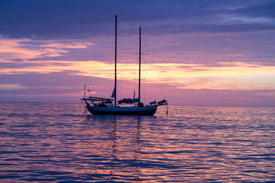 Boats sailing in sea at sunset