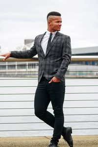 Full length of man standing against railing against sky