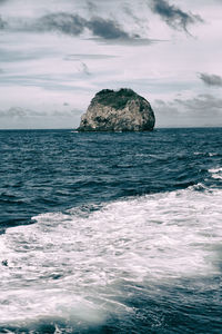 Rock formation in sea against sky