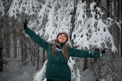 Portrait of smiling young woman standing on snow